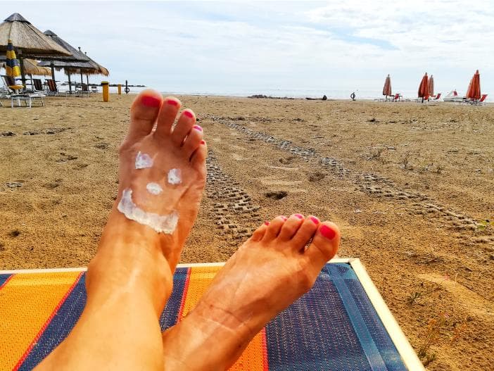 Sunscreen applied on feet on a beach